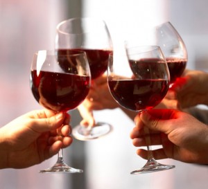 Close-up of four people's hands toasting with wine glasses